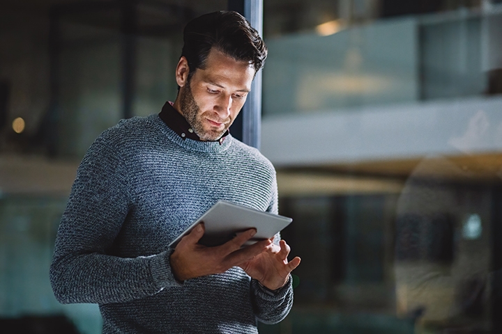  businessman standing alone in his office and using a tablet