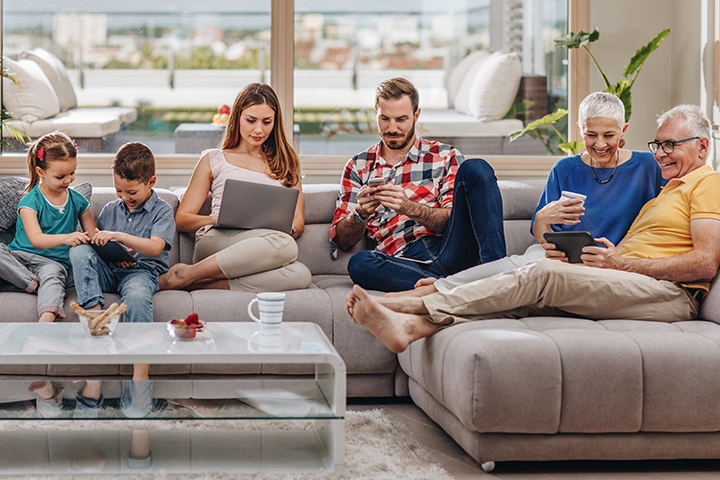 Smiling multi-generation family using wireless technology while relaxing at their penthouse.