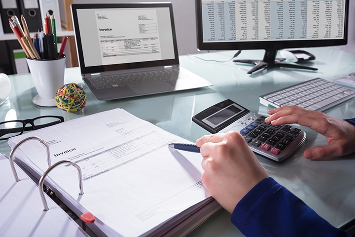 a businessperson's Hand calculating invoice at workplace