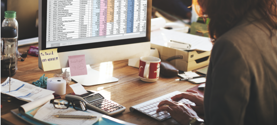woman working on a spreadsheet on her computer at her desk
