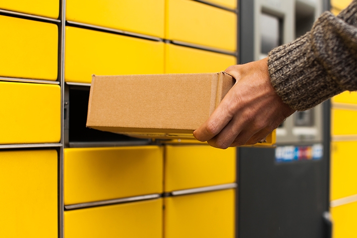 Yellow self-service post terminal machine. Man receiving a parcel from the machine