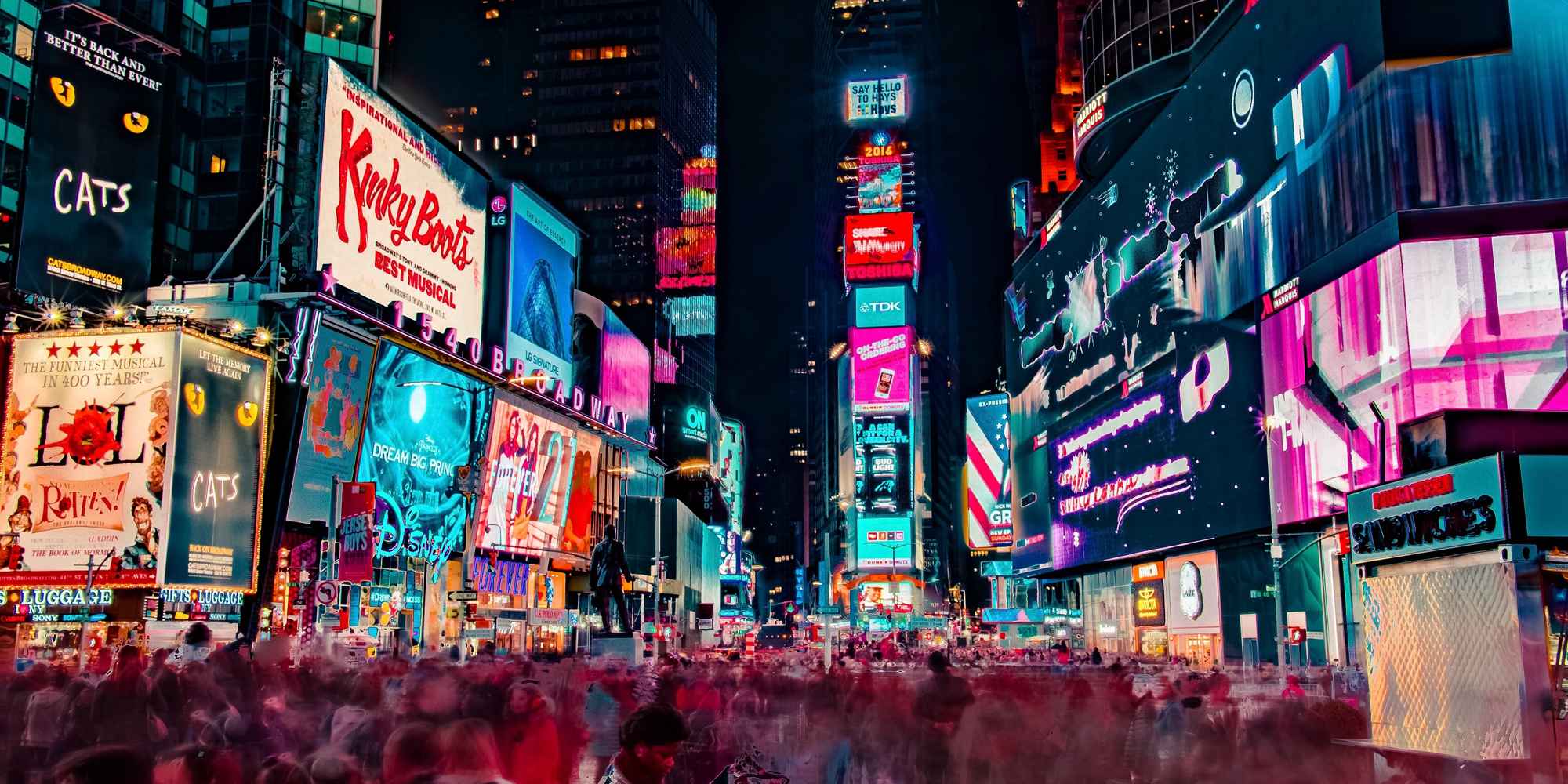 bustling city square at night with lit up billboards