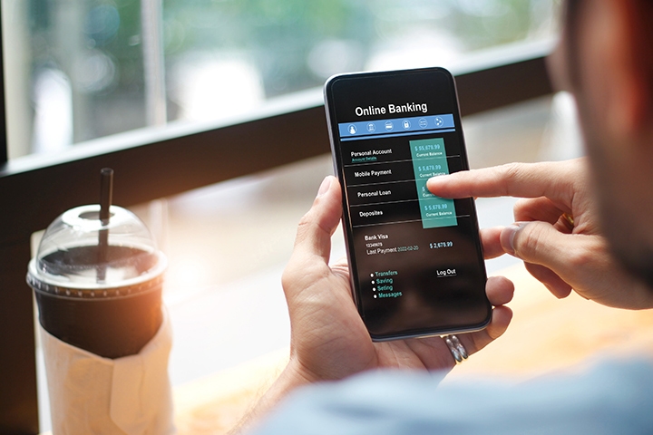 Shot of person using mobile banking on smartphone at desk