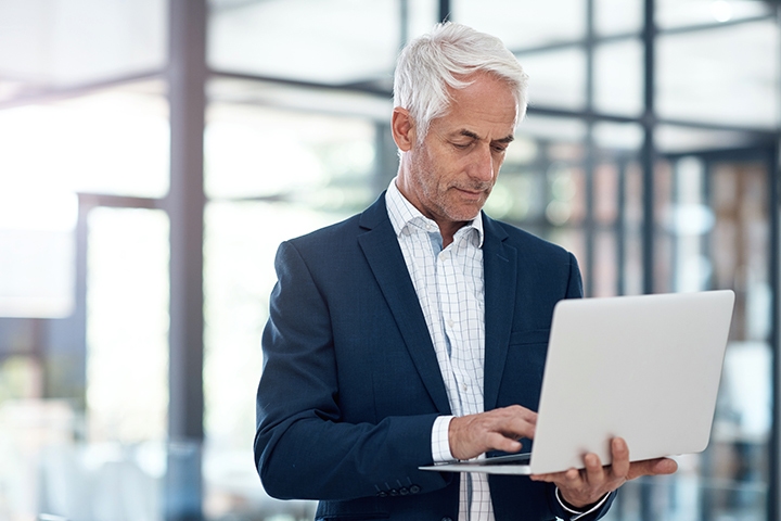 man working on his laptop in an office standig up