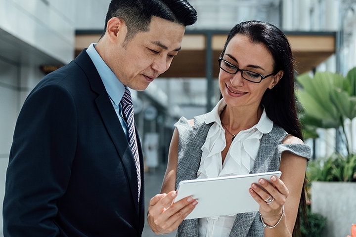 woman showing man information from her tablet in an office setting