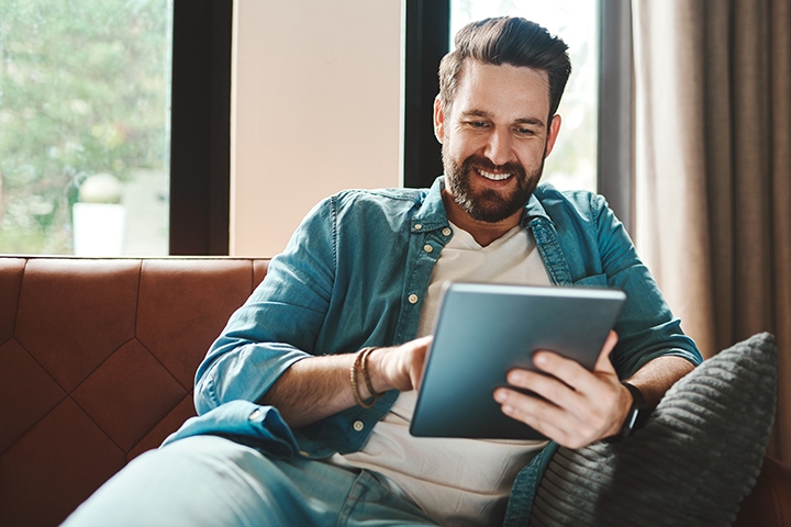 young man using a tablet while chilling on the sofa at home