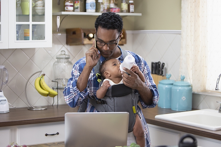 Single parent working from home, baby holder with a baby bottle