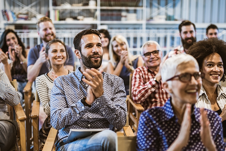 Crowd clapping, smiling, at a seminar industry event speech