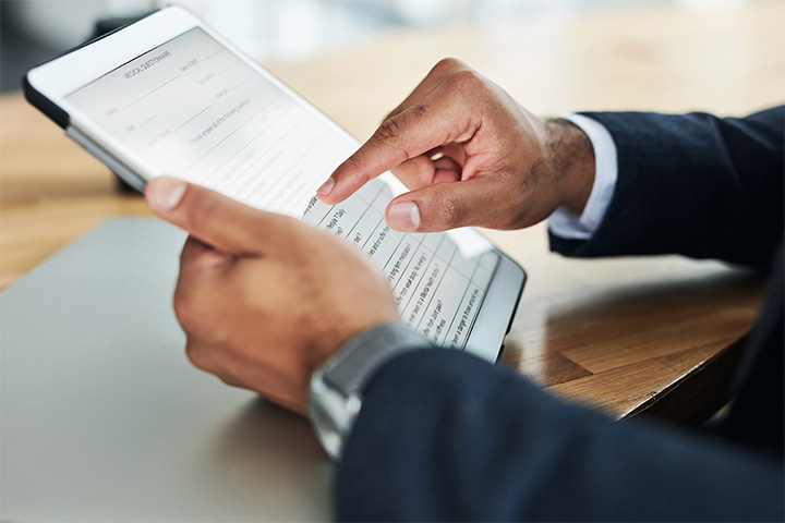 close up of man's hands, using his tablet to complete a document