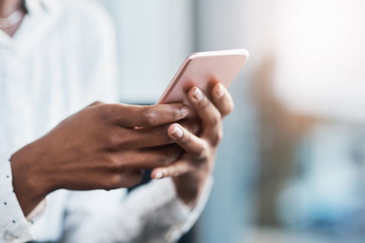Photo recadrée d'une femme d'affaires utilisant un téléphone portable dans un bureau moderne
