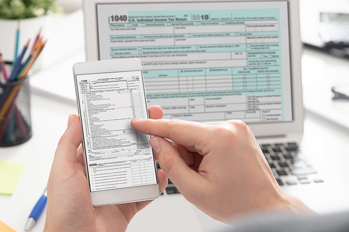 Person viewing tax documents on smartphone and laptop