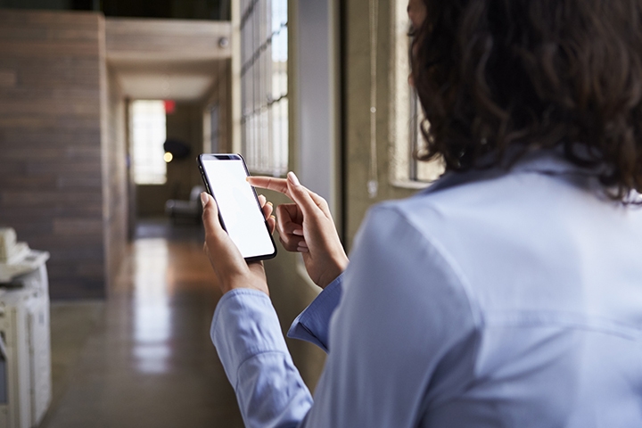 Businesswoman using her smartphone, products, services, office back view