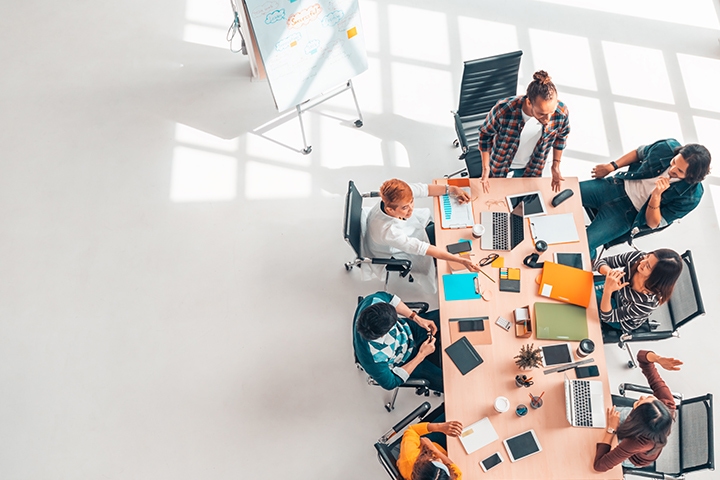 Aerial shot of a group of people working together at a table with laptops and papers