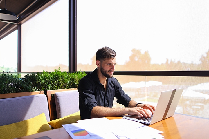 man working at his laptop by a window