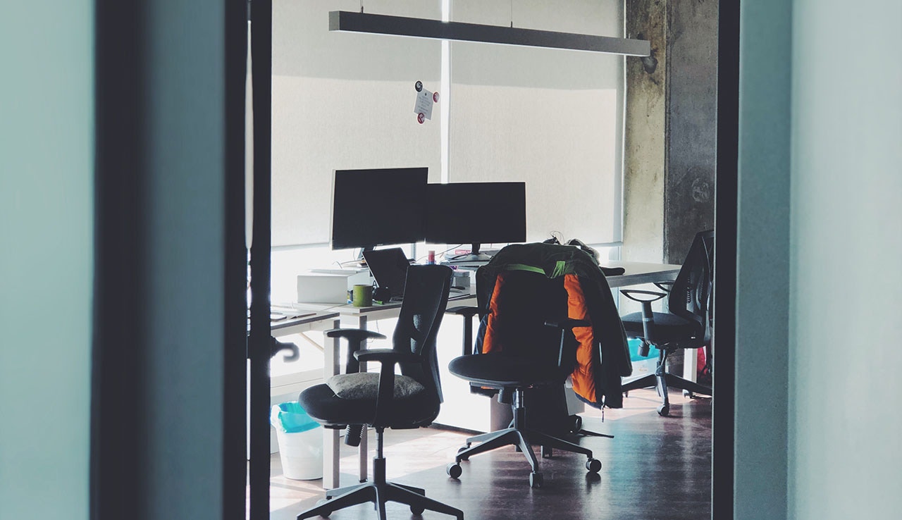 Desk chairs, monitors, and tables in an empty office