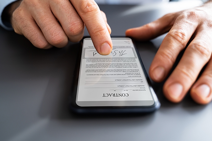 Man signing a contractual document using a smartphone