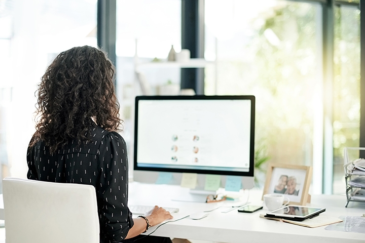 Rearview shot of a young businesswomen using a computer at her desk in a modern office