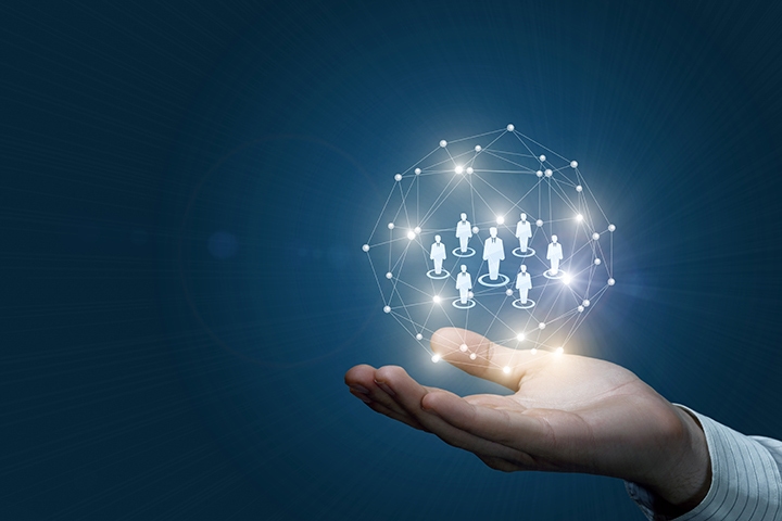 Un gros plan d'une main masculine tenant une sphère numérique de connexions sans fil avec des modèles de figure humaine à l'intérieur. Le concept de communication