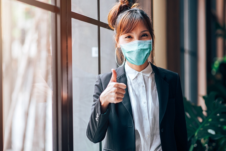 woman giving a thumbs up, wearing a mask