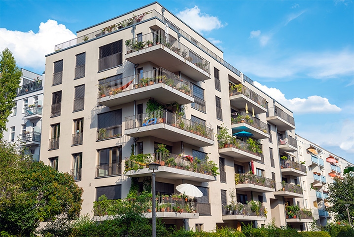 Moderner Wohnblock mit einer grünen Anlage und blauem Himmel