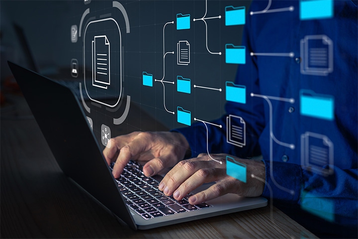 icons of files and documents around a computer with a man typing at night