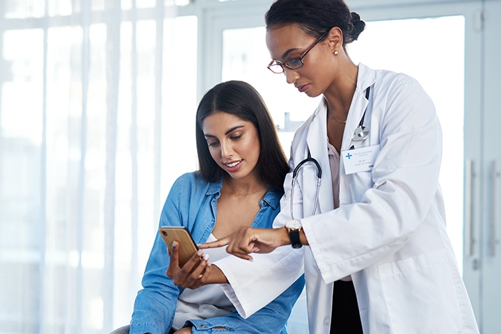 Doctor using smartphone with patient in office