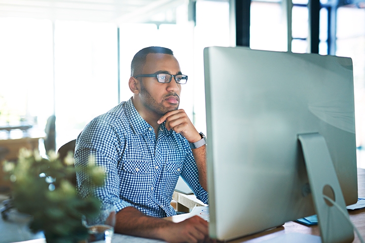 quadient-integration-messagemedia-helps-global-insurance-provider-meet-its-omnichannel man working at his computer and looking intensely at something on his screen
