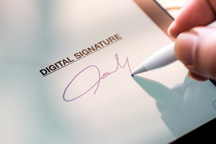 Person signing their signature digitally with a tablet and stylus pen