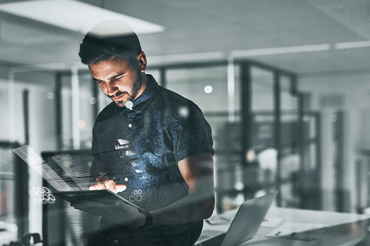 Young business professional  working on his tablet with graphs and digital information emitting from tablet