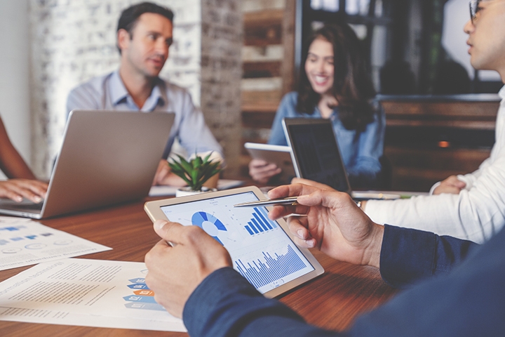 business workers sitting at a conference table analysing data trends