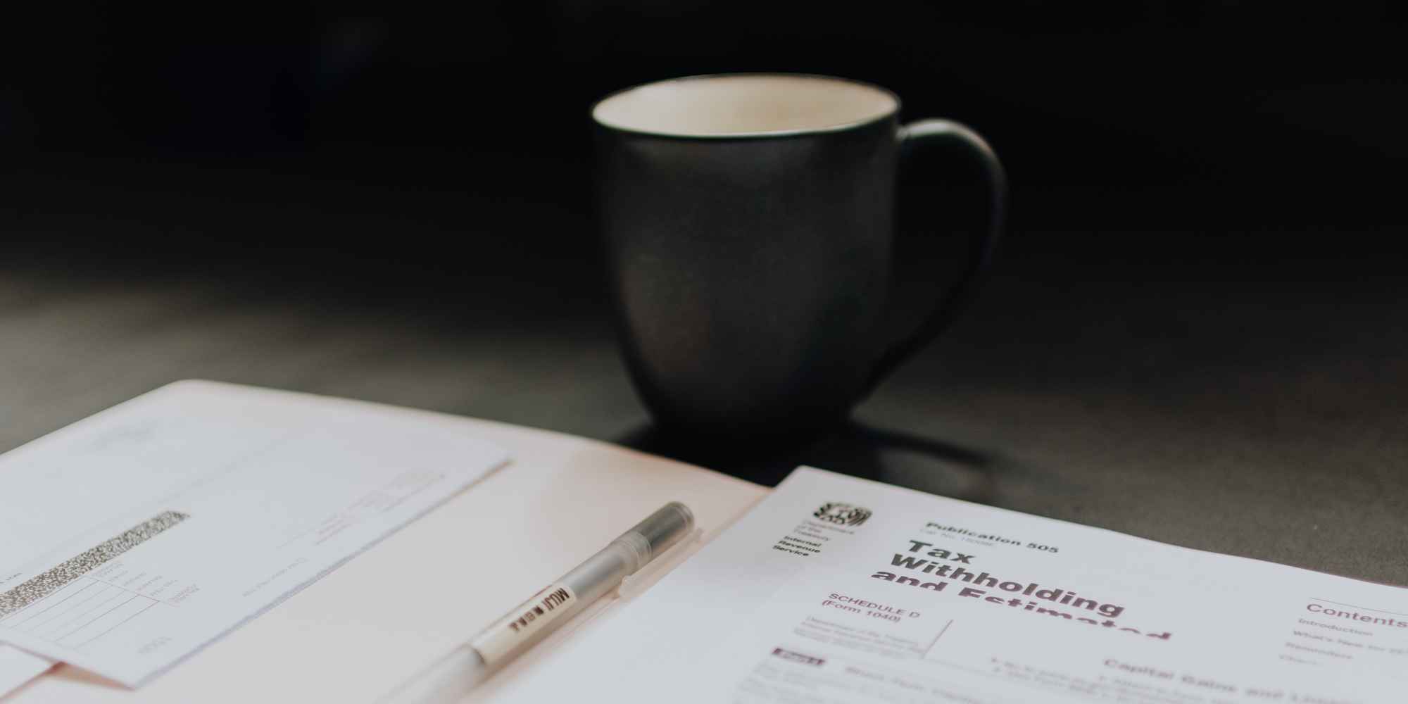 tasse de café sur un bureau à côté d’un livre ouvert avec un stylo à l’intérieur
