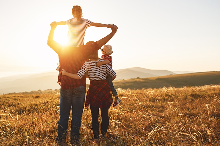 Happy family: mother, father, children son and daughter on nature walk on sunset