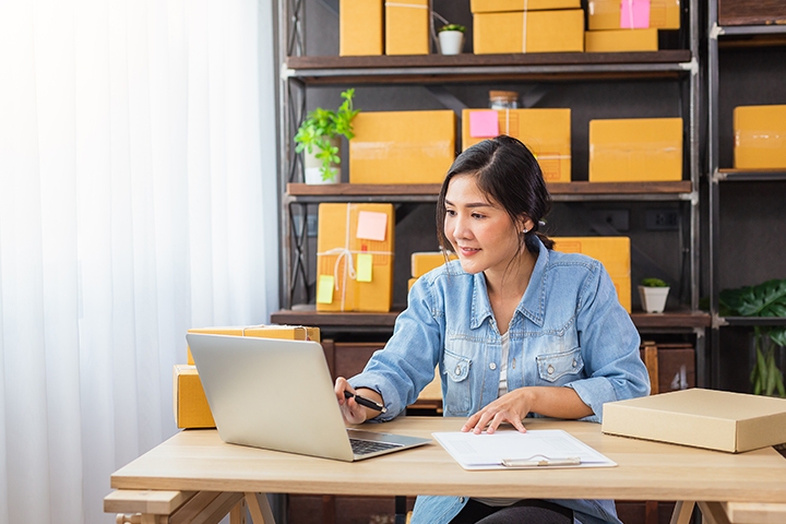 woman working at her computer in her home office with storage boxes behind her 