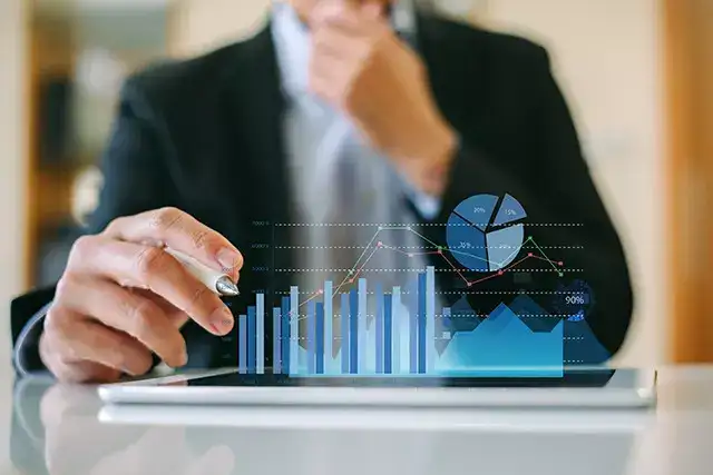 Businessman looking at projection of graphs in front of him on the desk