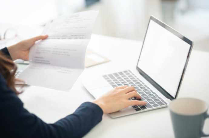 woman holding an invoice and using the laptop woman holding an invoice and using the laptop