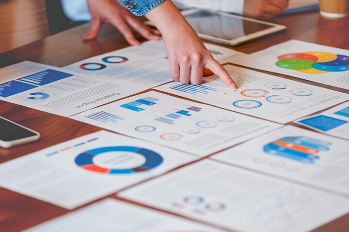 woman analyzing documents on table featuring dynamic graphs and charts