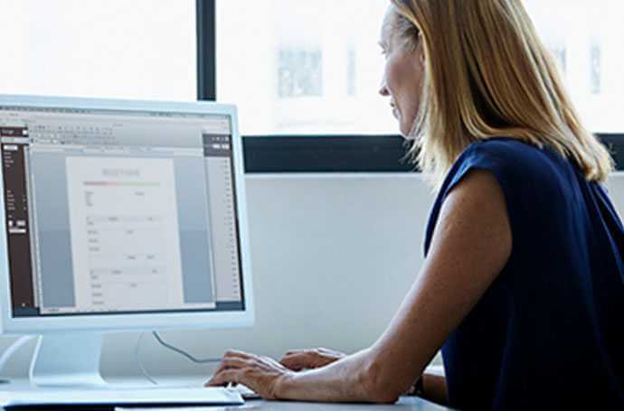 a middle-aged blond woman working in front of a screen side view