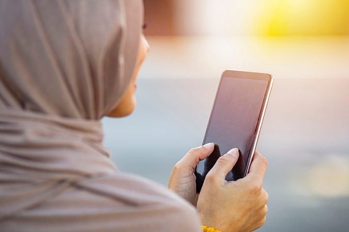 femme portant un hijab sur son téléphone à l’extérieur