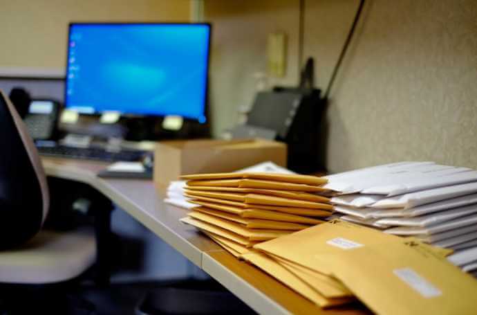 mail piled on an office desk mail piled on an office desk