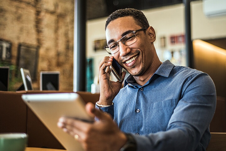 man on mobile phone while looking at tablet