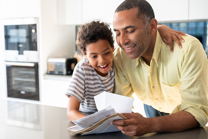 father and son reading printed mail documents