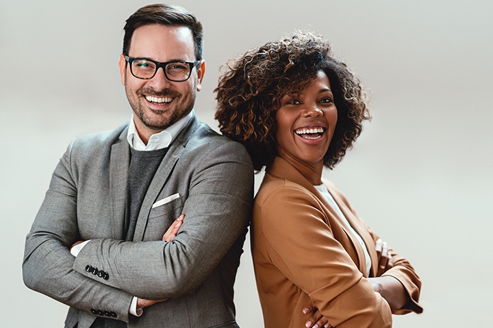 cheerful multi ethnic business colleagues wearing suits and looking at camera