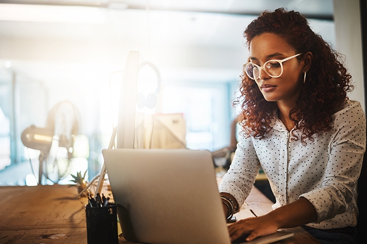 young woman using a laptop late at night at work