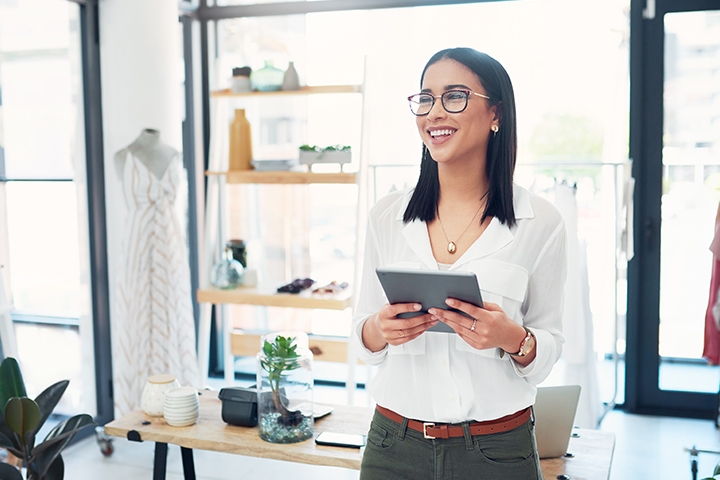 Female business owner using her tablet while standing in her store