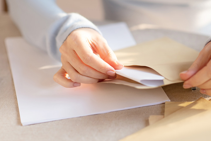 Female hands inserting a letter in an envelope