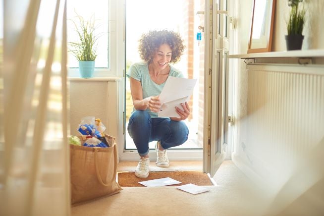 image of a person picking up letters from a doormat
