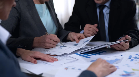 3 people sat at a table reviewing documents