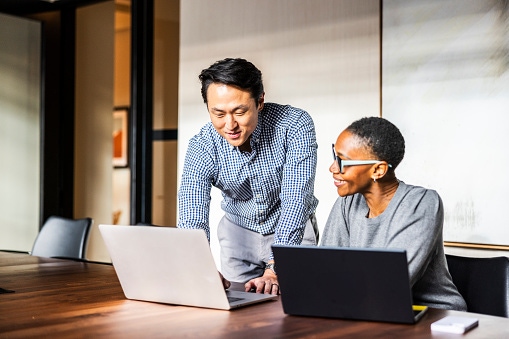 Two individuals in front of computers