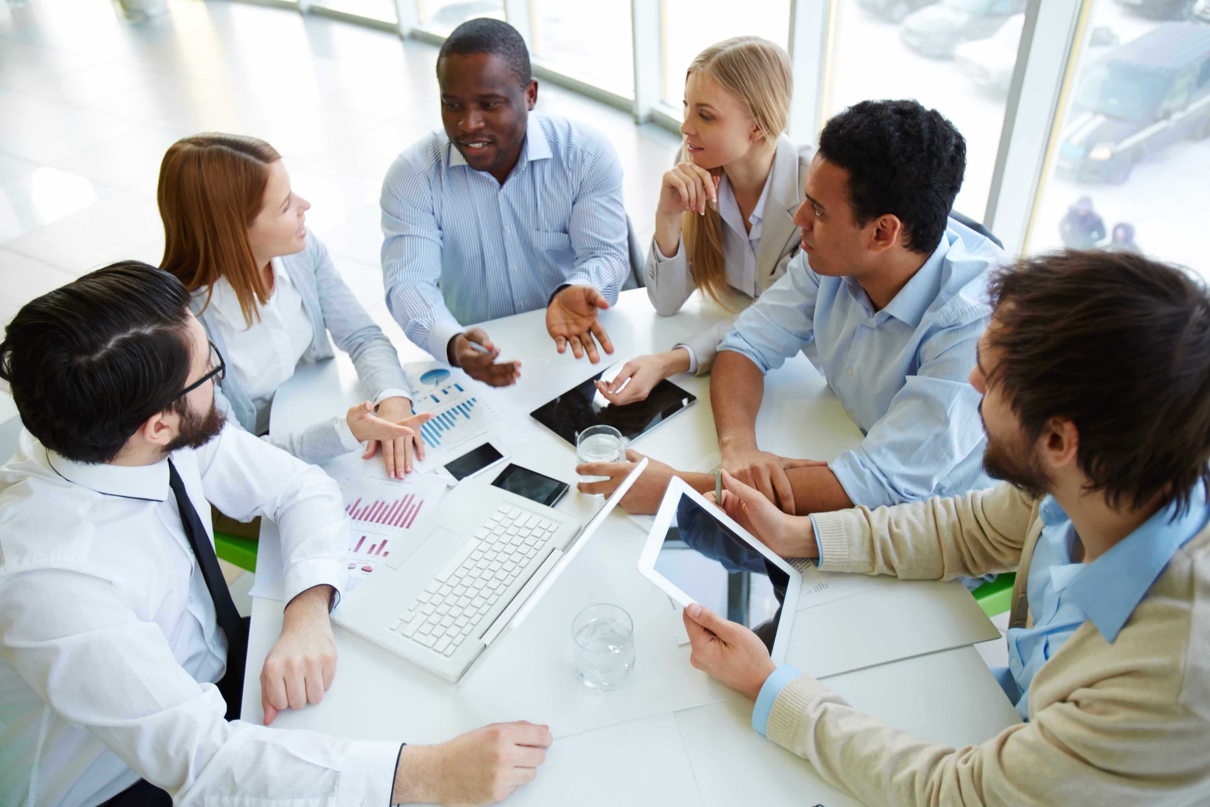 Team of business professionals seated around a conference table reviewing documents and discussing strategy during a meeting.