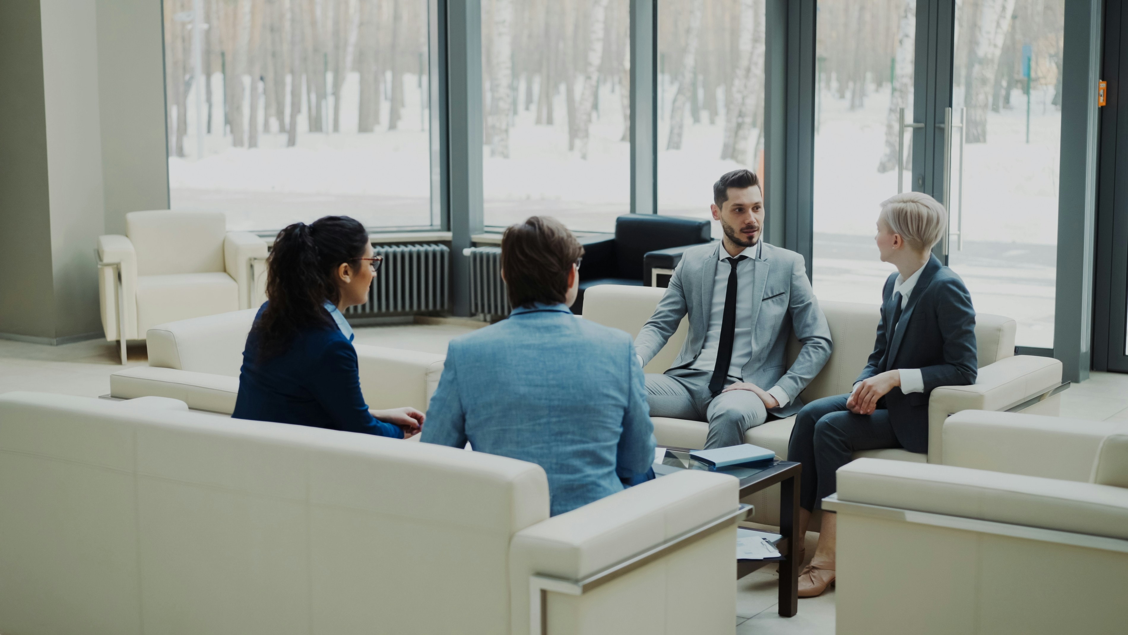 A group of business professionals sitting together in a modern office lounge, discussing finance process improvements and strategies related to Accounts Payable Transformation